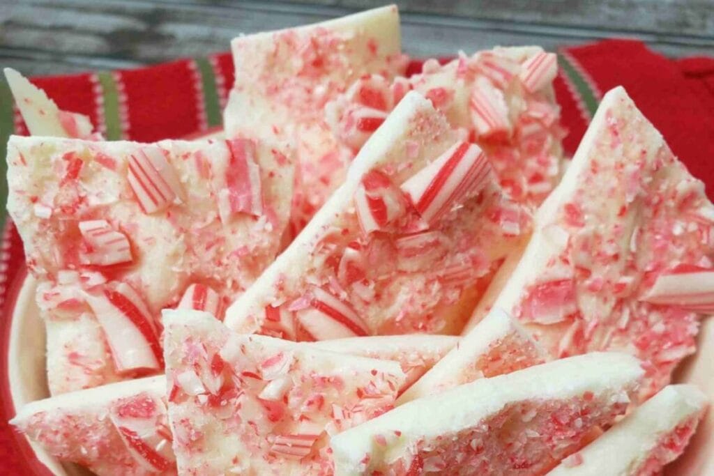 Close-up of peppermint bark pieces with crushed candy canes in a bowl.