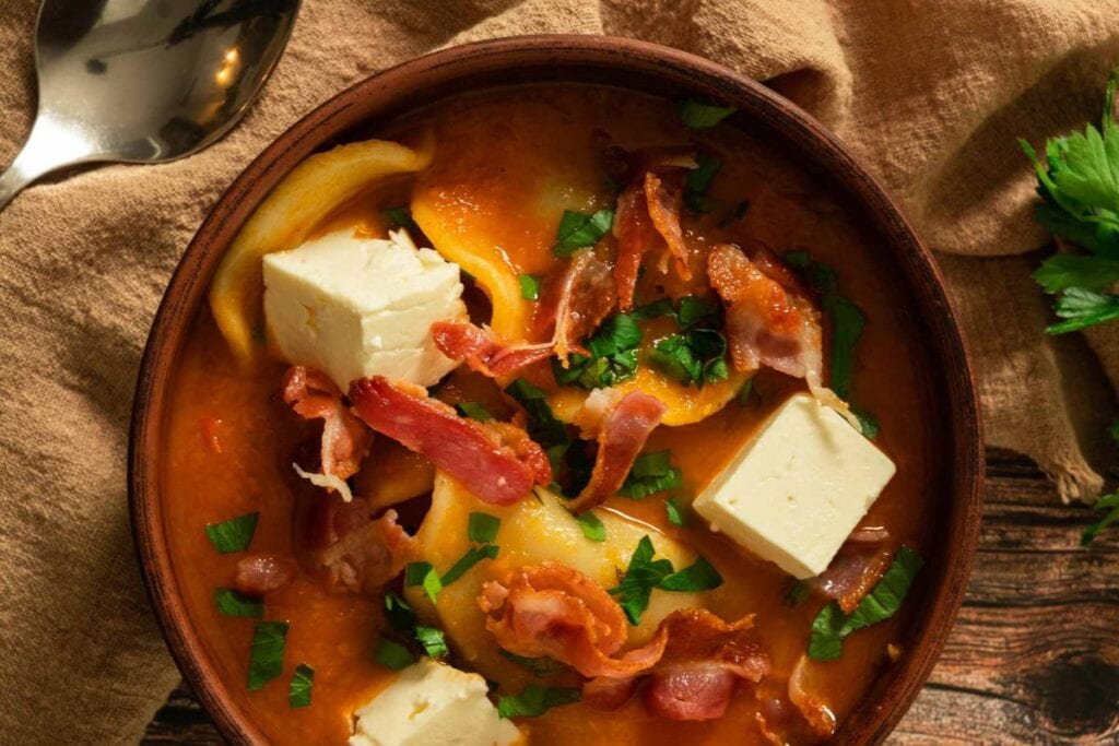 Pierogi soup with bacon, cheese, and parsley in bowl.
