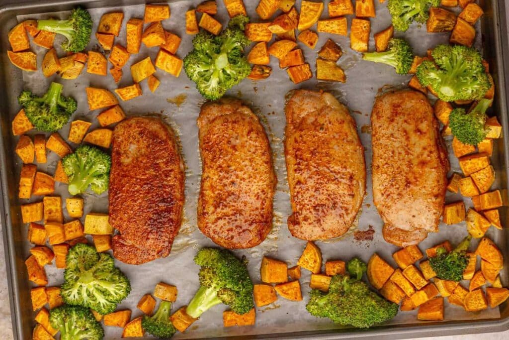 Sheet pan dinner with pork chops, sweet potatoes, and broccoli.