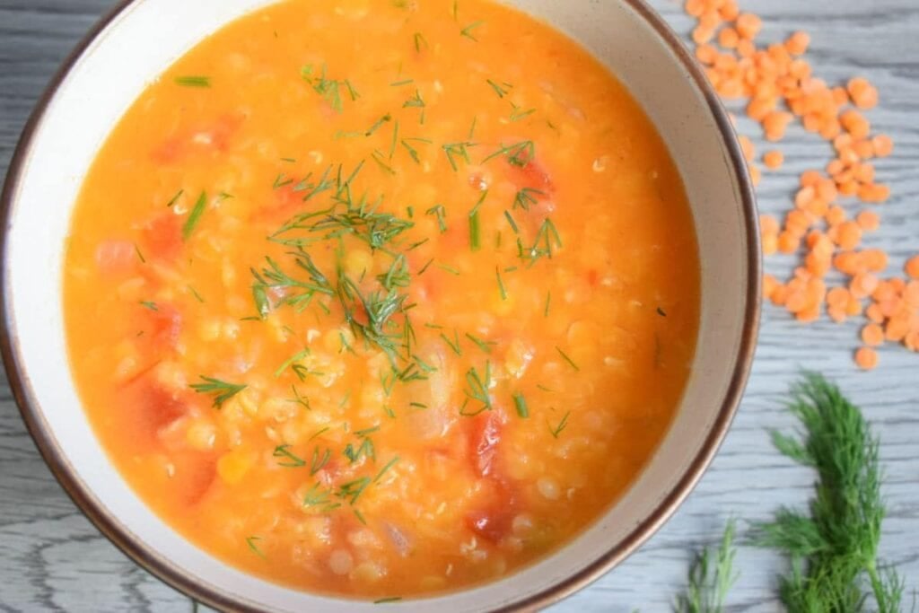 Red lentil soup in a bowl with dill garnish.