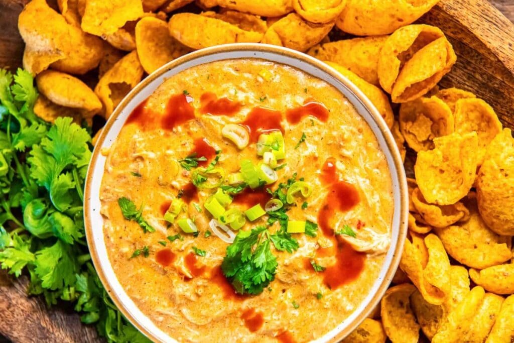 Chicken enchilada dip with tortilla chips, cilantro, and green onion garnish.