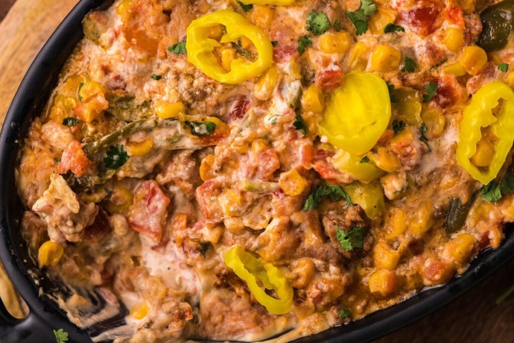 Close-up of taco dip in a slow cooker, topped with peppers and cilantro.