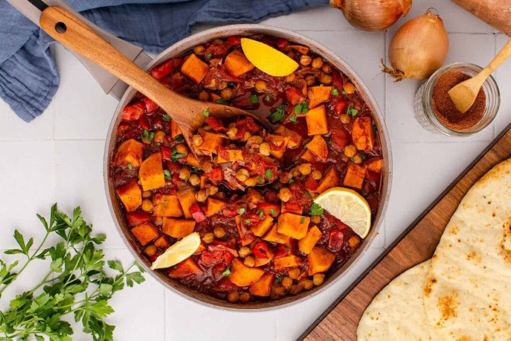Overhead shot of sweet potato skillet with chickpeas, lemon, and naan bread.