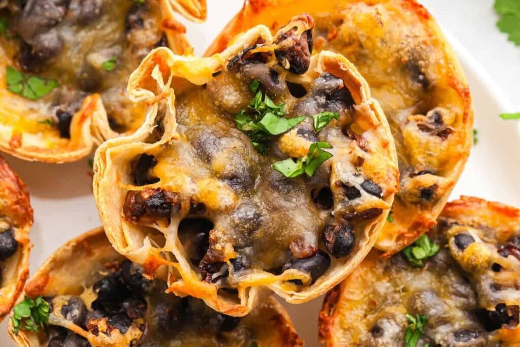 Close-up of mini taco bites with black beans, cheese, and parsley.