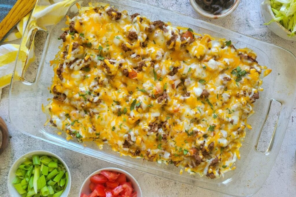 Overhead shot of taco casserole with cheese in a glass baking dish.