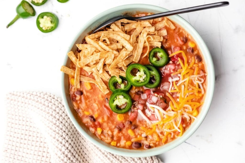 Overhead shot of tortilla soup with tortilla strips, cheese, and jalapenos.