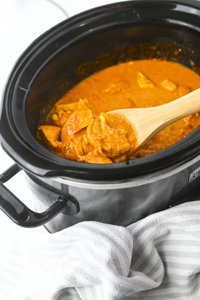Chunks of butter chicken in a rich sauce inside a crockpot.
