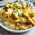 Shredded chicken and gravy served over mashed potatoes with parsley.