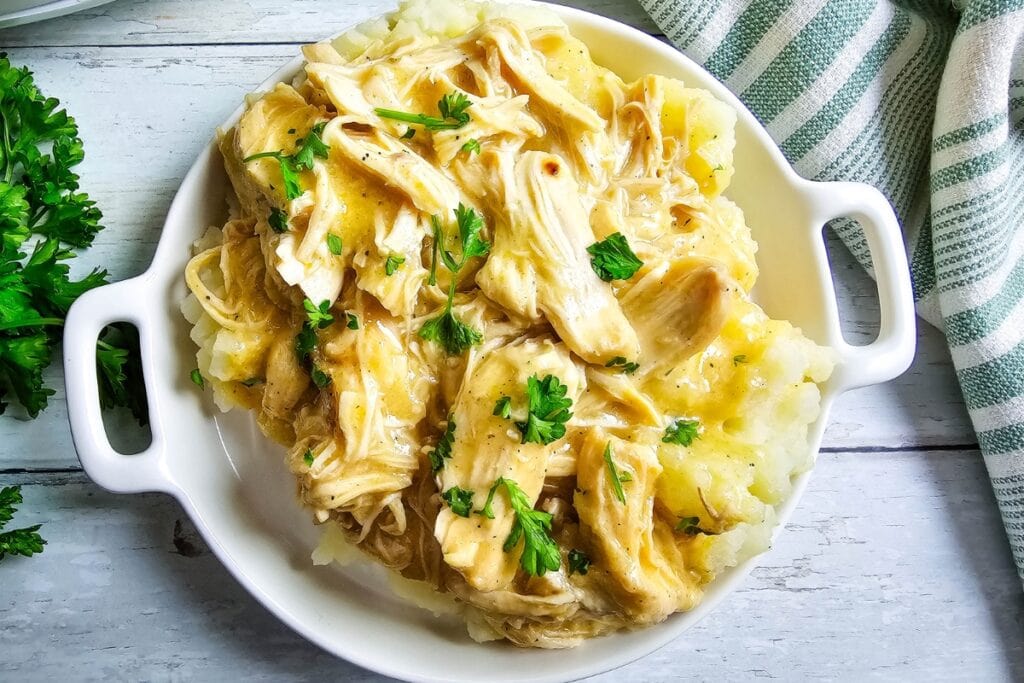 Shredded chicken and gravy served over mashed potatoes with parsley.