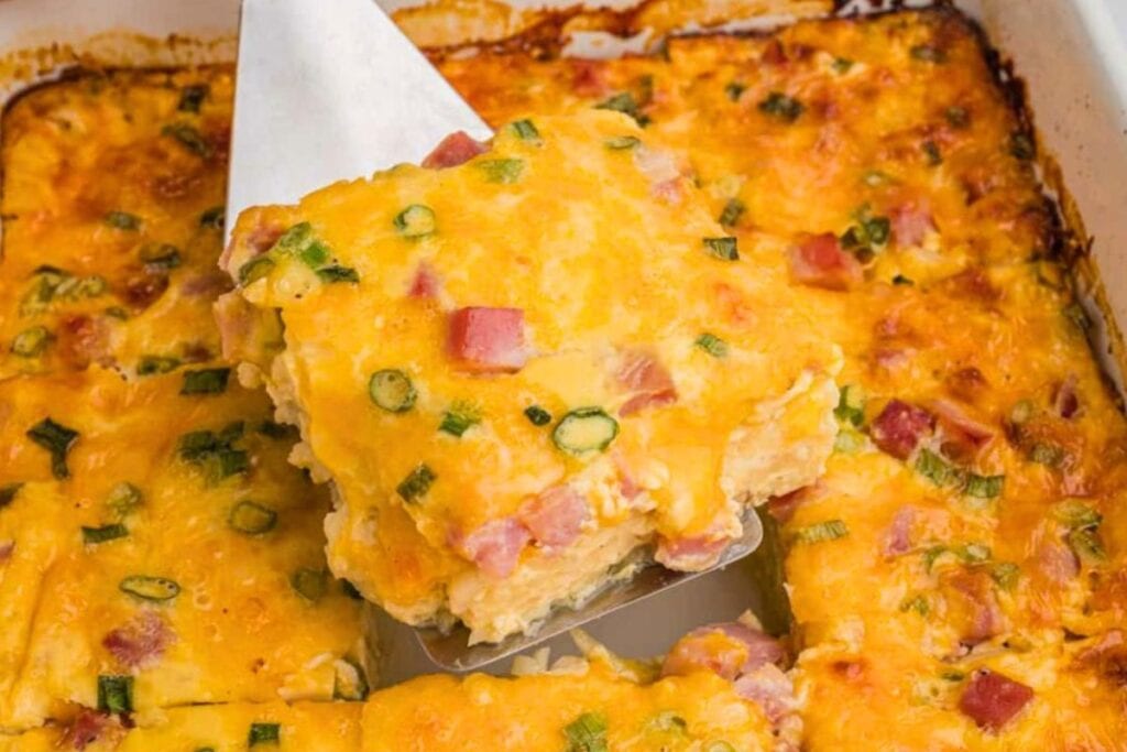 breakfast casserole getting served in white casserole dish.