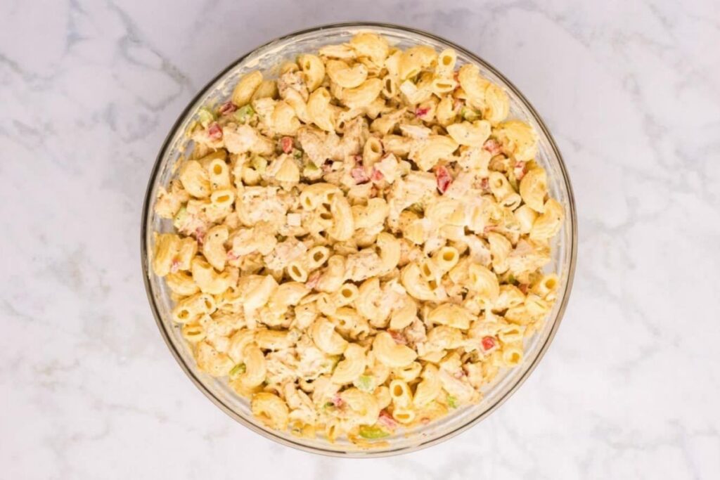 Overhead shot of chicken macaroni salad with mayonnaise dressing in a glass bowl.