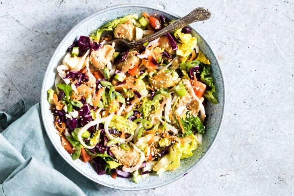 Overhead view of Chinese chicken salad with cabbage, carrots, and sesame seeds in a bowl.