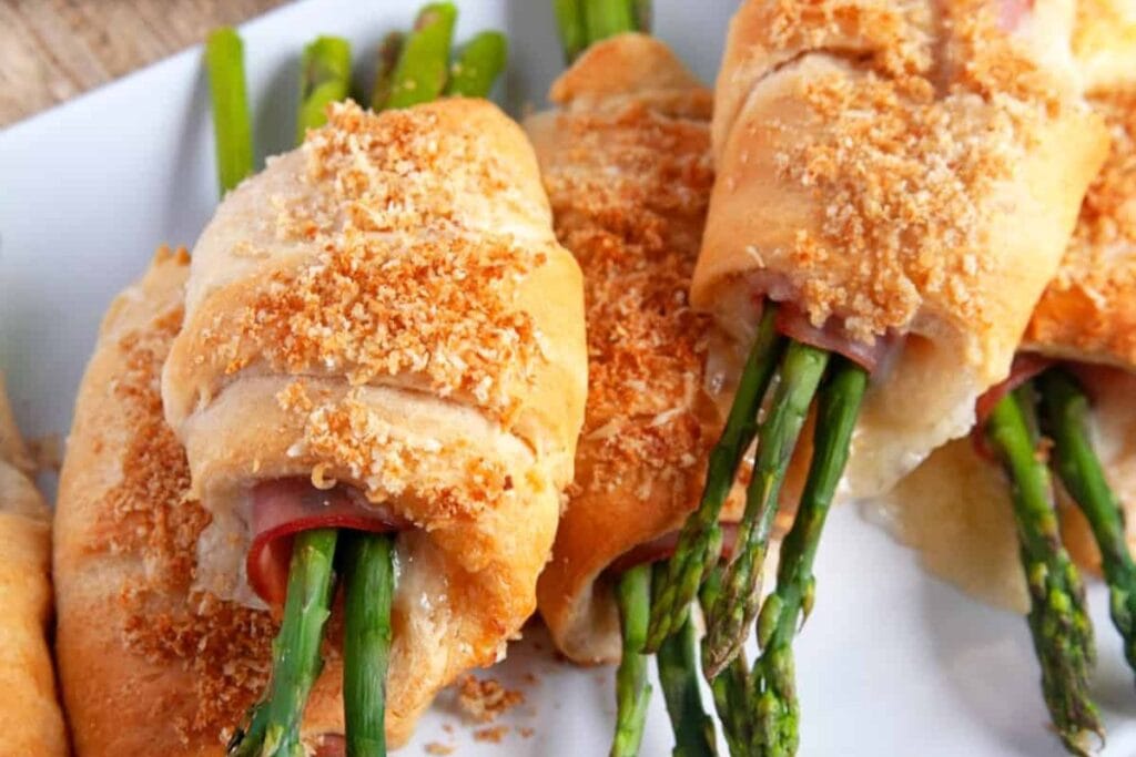 A close up shot of ham and cheese crescent rolls with asparagus.