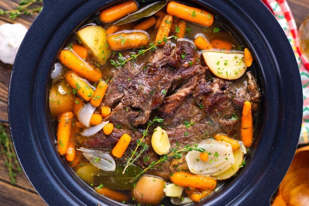 A close up shot of slow cooker pot roast with garlic red wine.