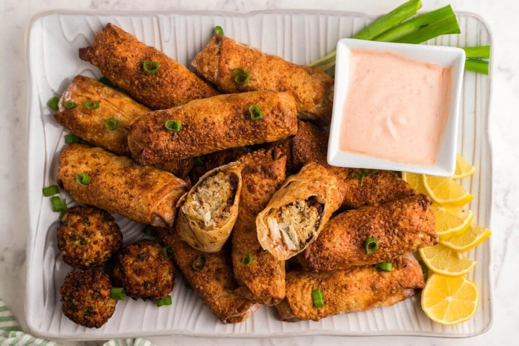 Air fryer crab cake egg rolls with fire sauce on a plate.