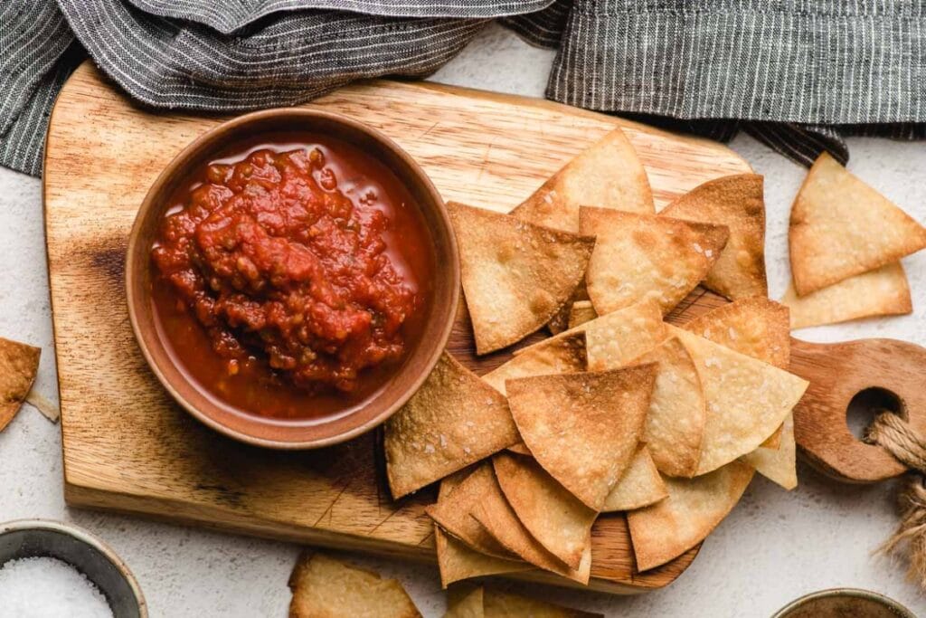 Air fryer tortilla chips on a wooden board.