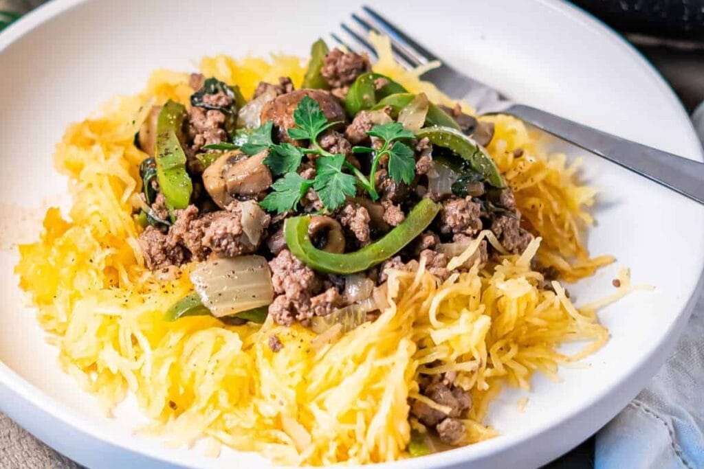 Baked spaghetti squash with beef and vegetables on a plate.