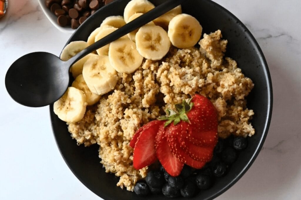 Banana peanut butter quinoa breakfast topped with fruit on a plate.
