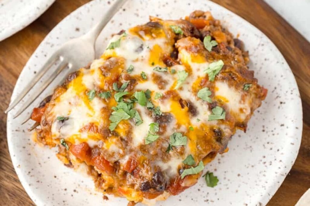 Beef enchilada casserole with corn tortillas on a plate.