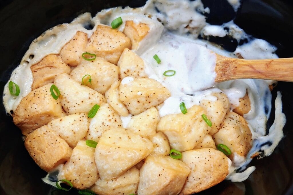 Biscuits coated in creamy sausage gravy in a slow cooker.