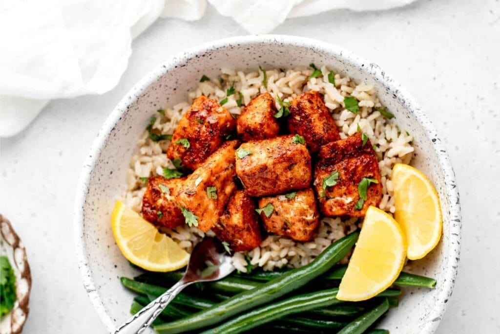 Blackened salmon bites and green beans on a plate.