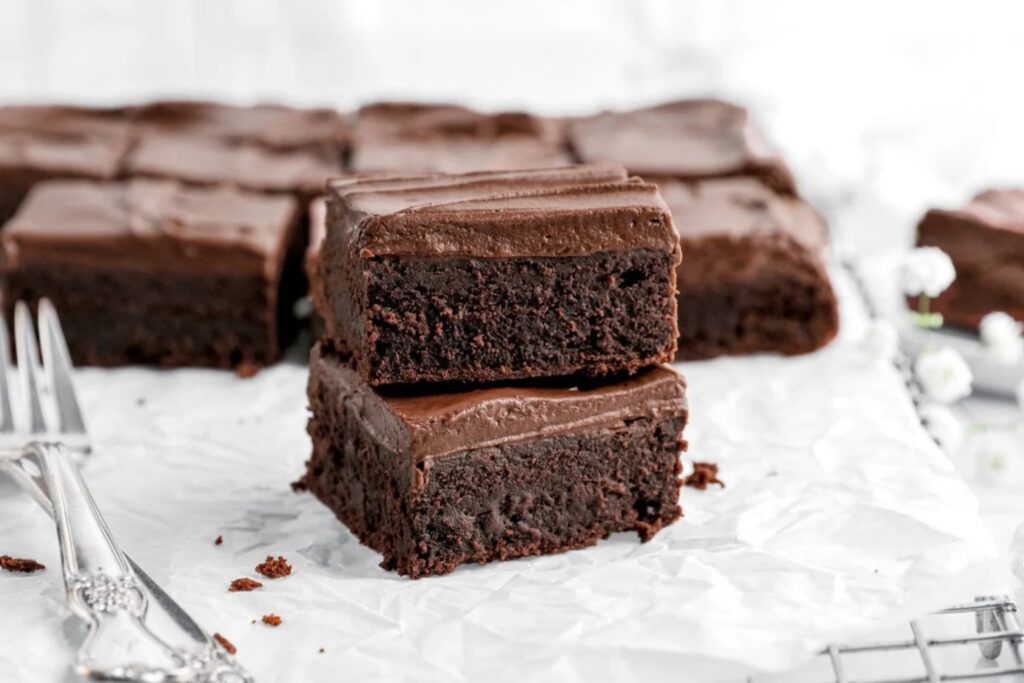 Chewy fudge frosted brownies on a cooling rack with parchment paper.