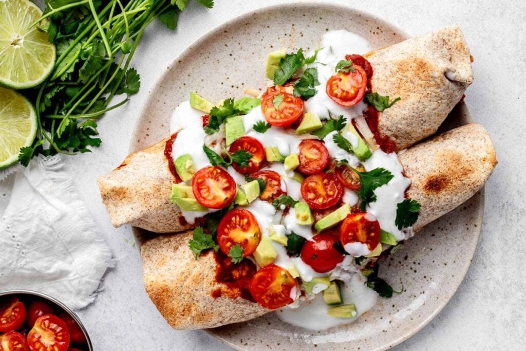 Chicken enchiladas on a plate with fresh toppings.