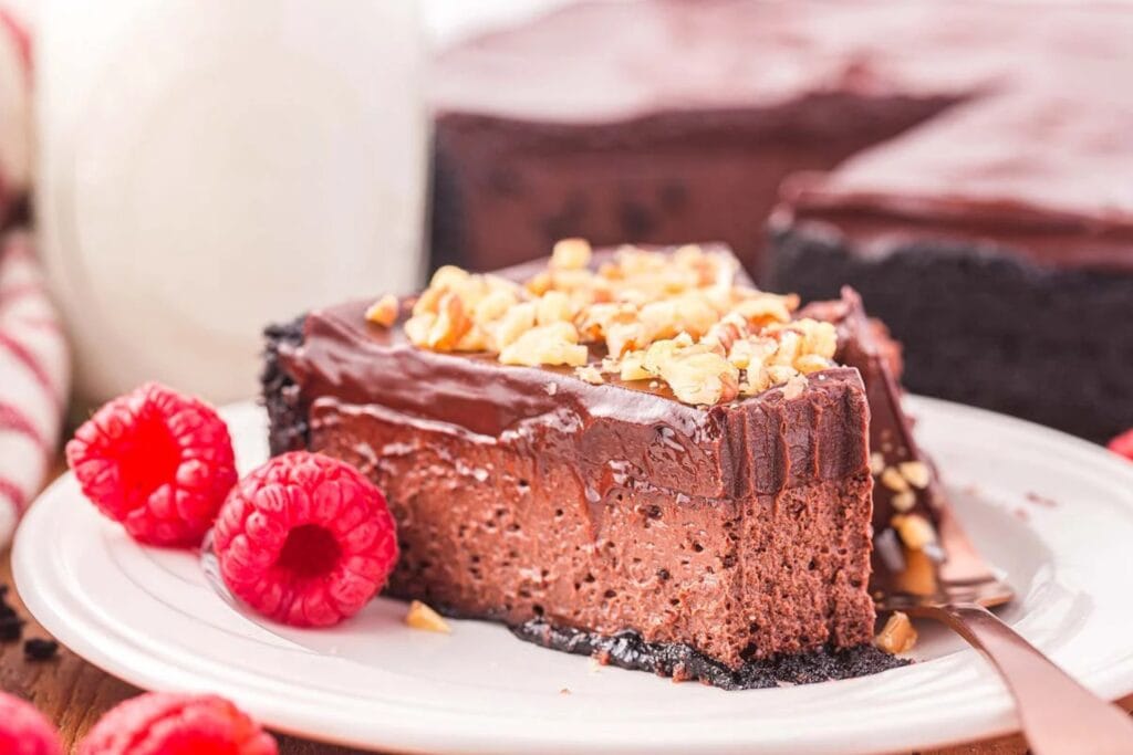 Chocolate cheesecake slice topped with chopped nuts on a plate.