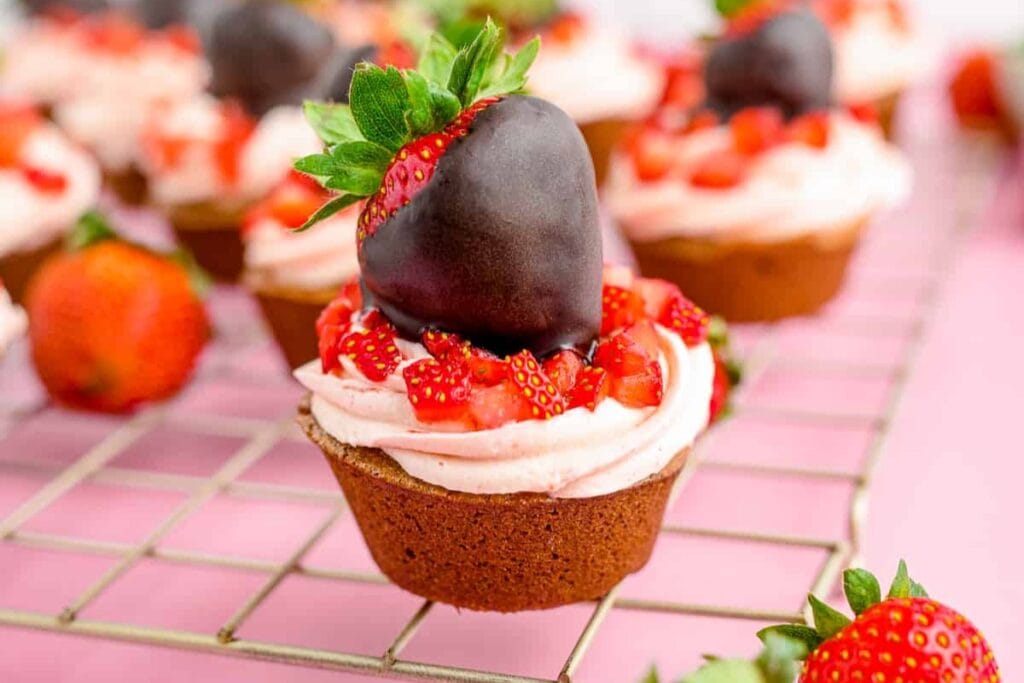 Chocolate strawberry cupcakes topped with frosting and chocolate-dipped strawberries.