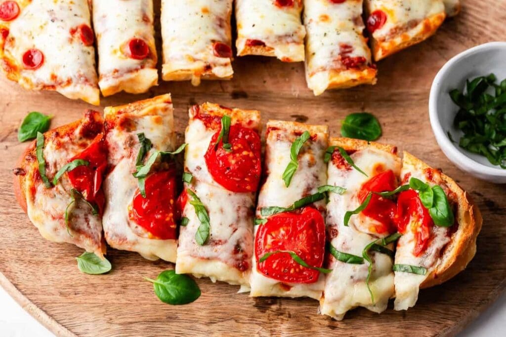 French bread pizza sliced and served on a wooden board.