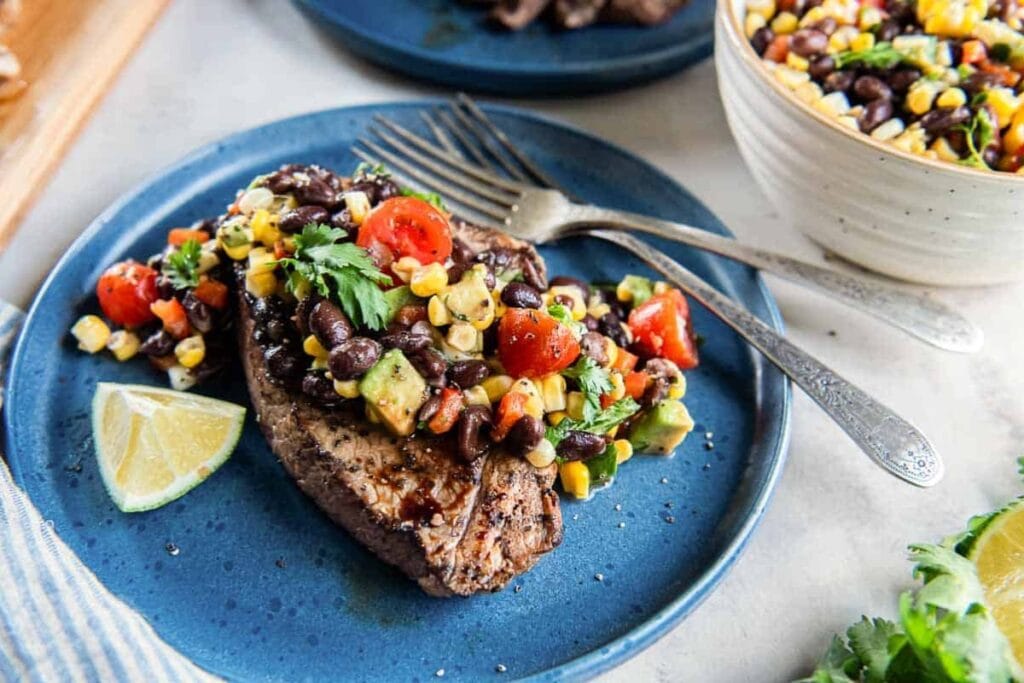 Grilled steak with corn and black bean salsa on a plate.