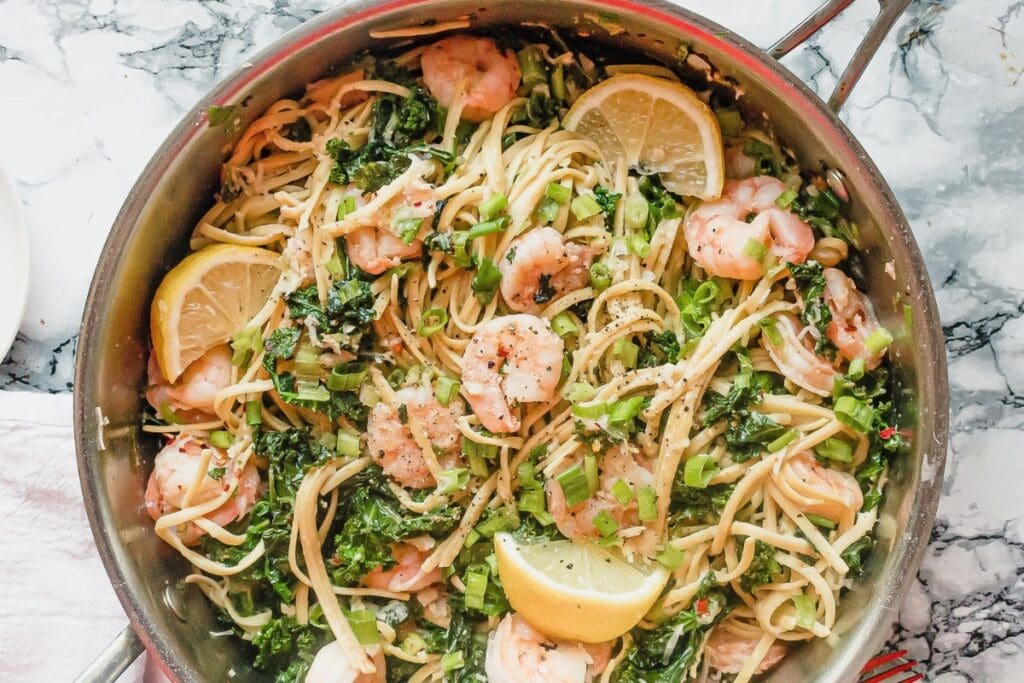 Lemon shrimp pasta with kale in a skillet.