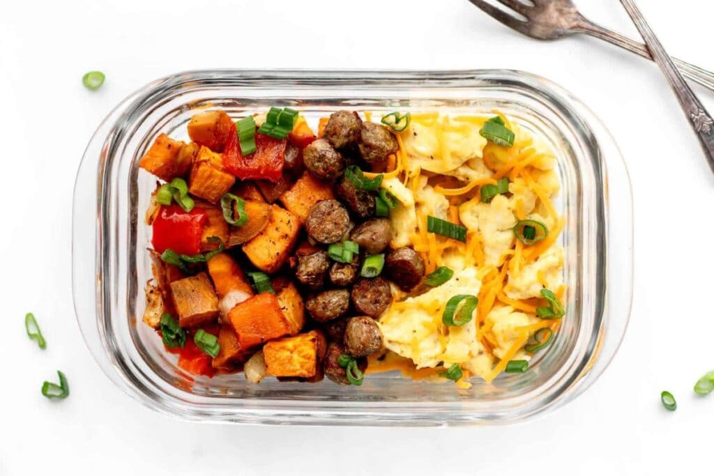 Meal prep breakfast bowls with eggs and vegetables in a glass baking dish.