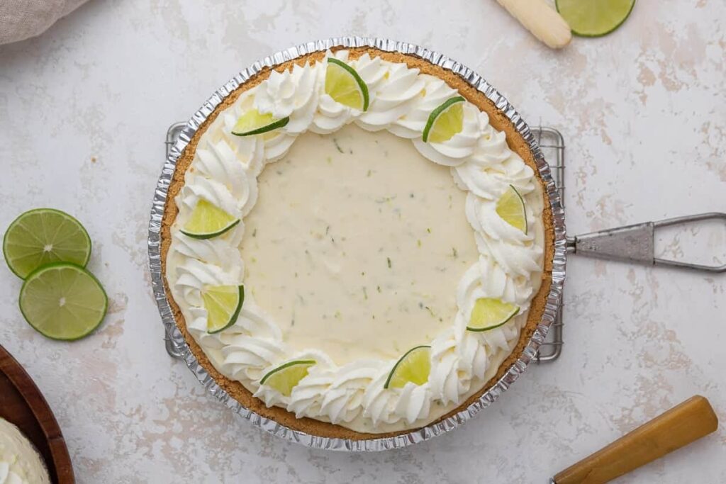 No-bake key lime pie topped with whipped cream and lime slices.