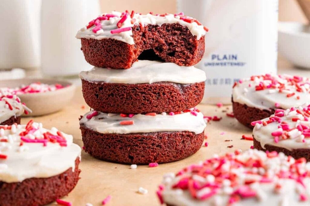 Red velvet cake donuts with cream cheese icing and sprinkles.