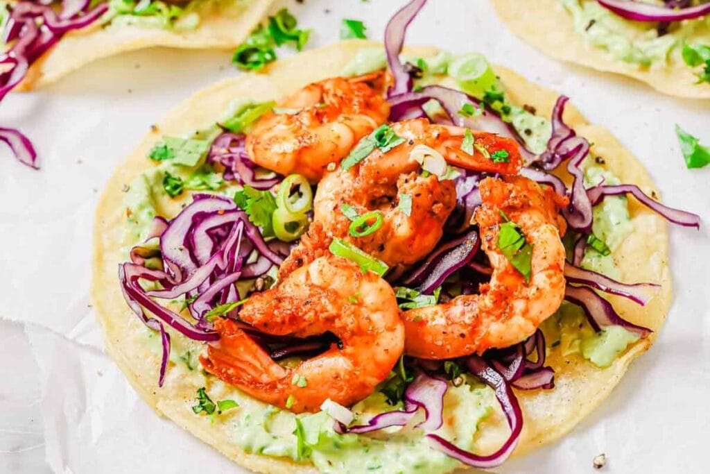 Spicy shrimp tostada with jalape&ntilde;o avocado sauce on parchment paper.