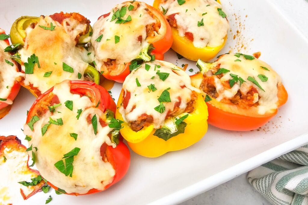 Stuffed bell peppers with melted cheese in a baking dish.