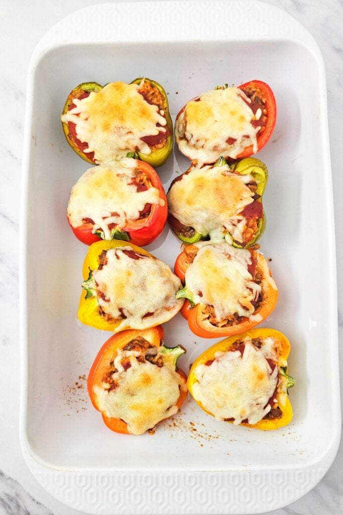 Process shot of baked stuffed bell peppers in a baking dish.