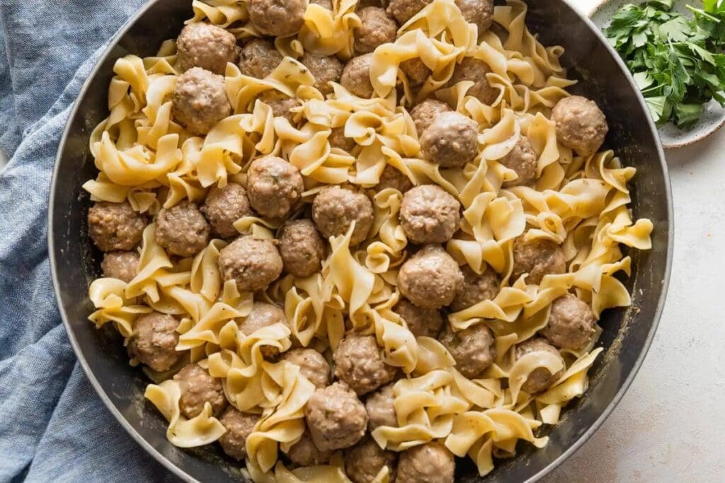 Swedish meatballs with egg noodles in a skillet.
