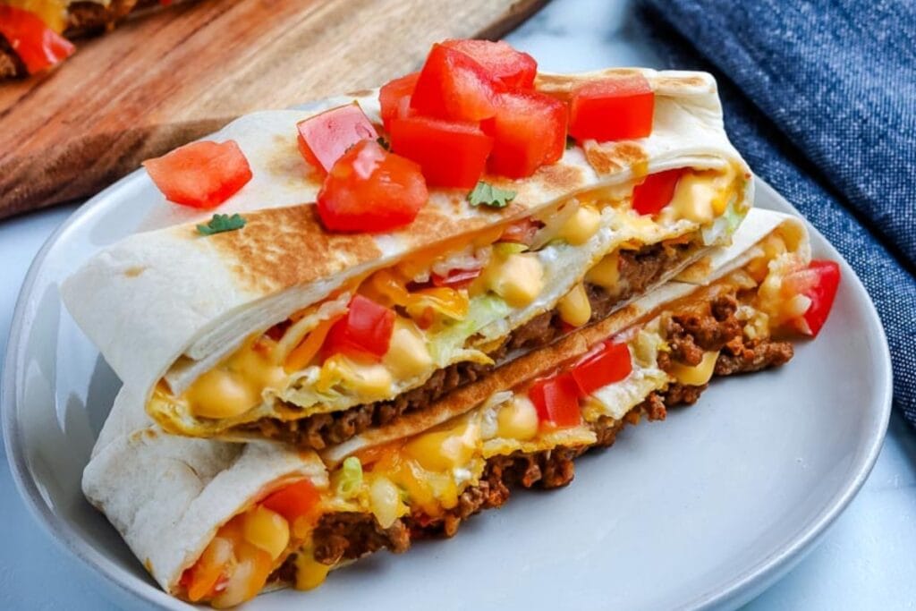 Taco bell crunchwrap supreme cut in half on a plate.
