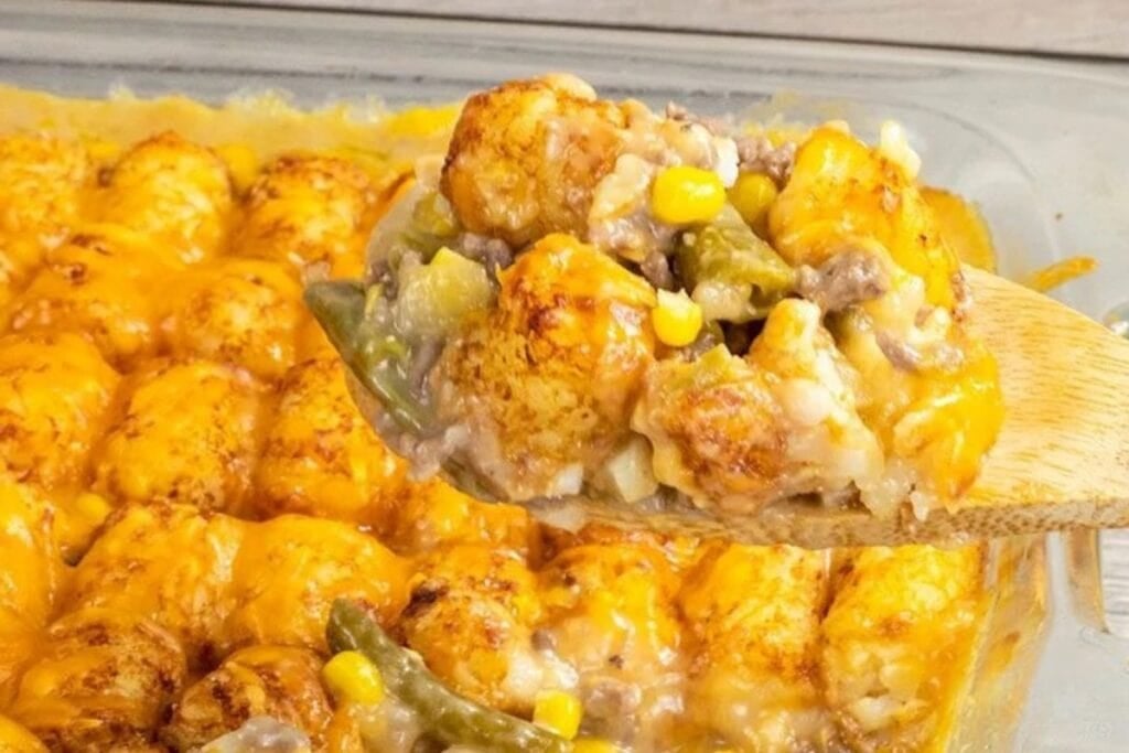 Close-up of tater tot casserole on a wooden spoon.
