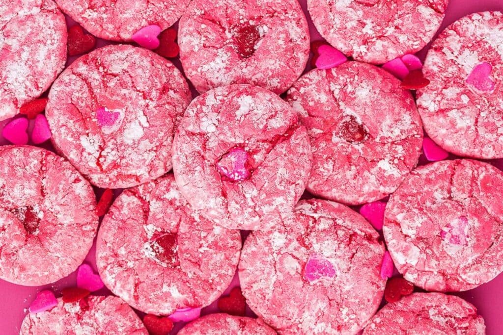 Valentine crinkle cookies with powdered sugar and heart sprinkles.