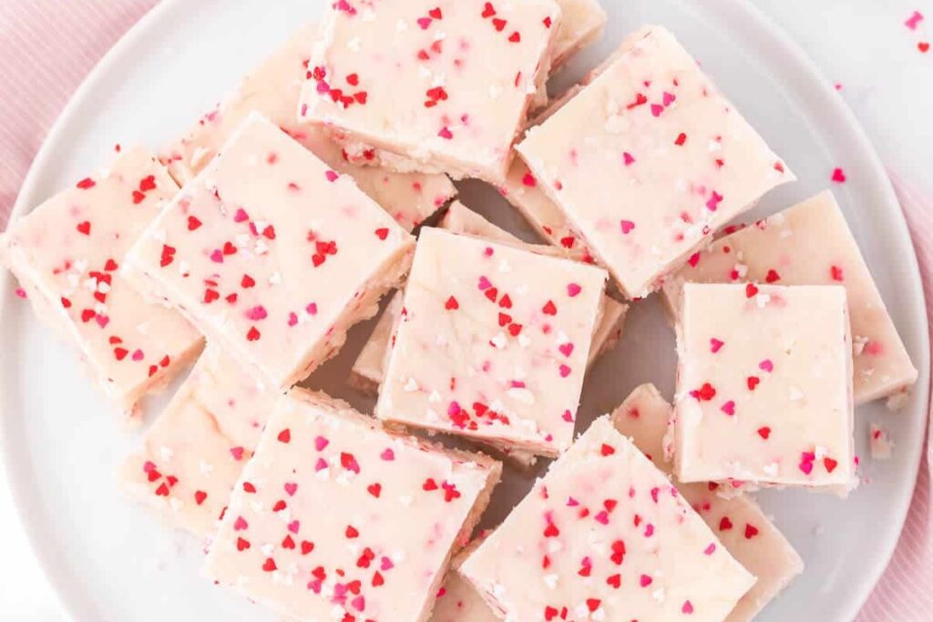 Valentine’s Day fudge squares with pink and red heart sprinkles on a plate.