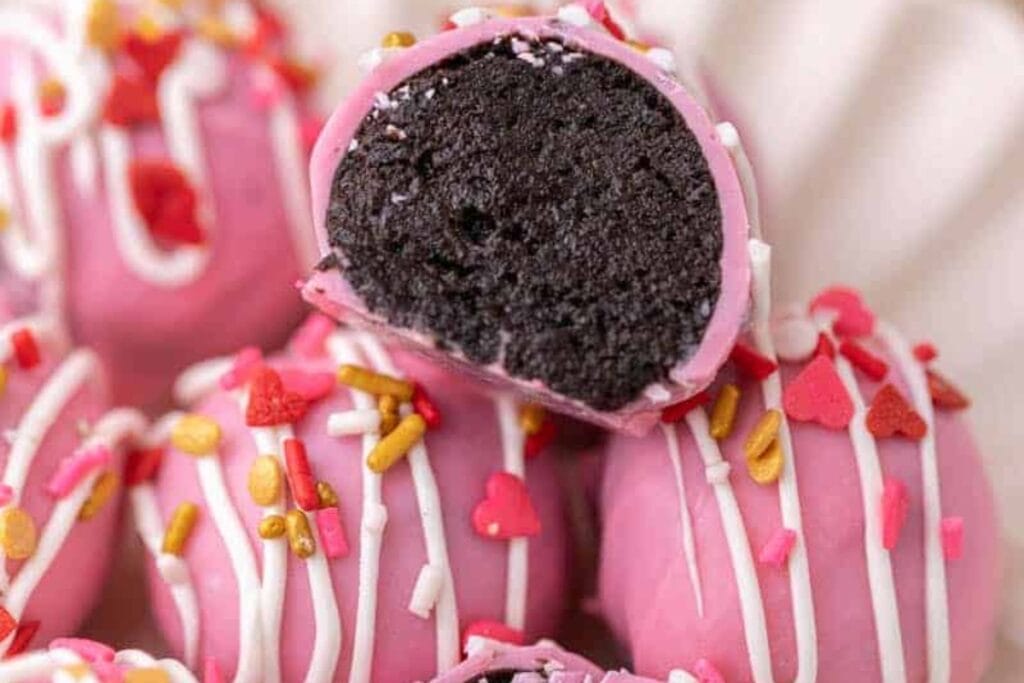 Valentine&rsquo;s Day Oreo truffles with pink coating, white drizzle, and sprinkles.