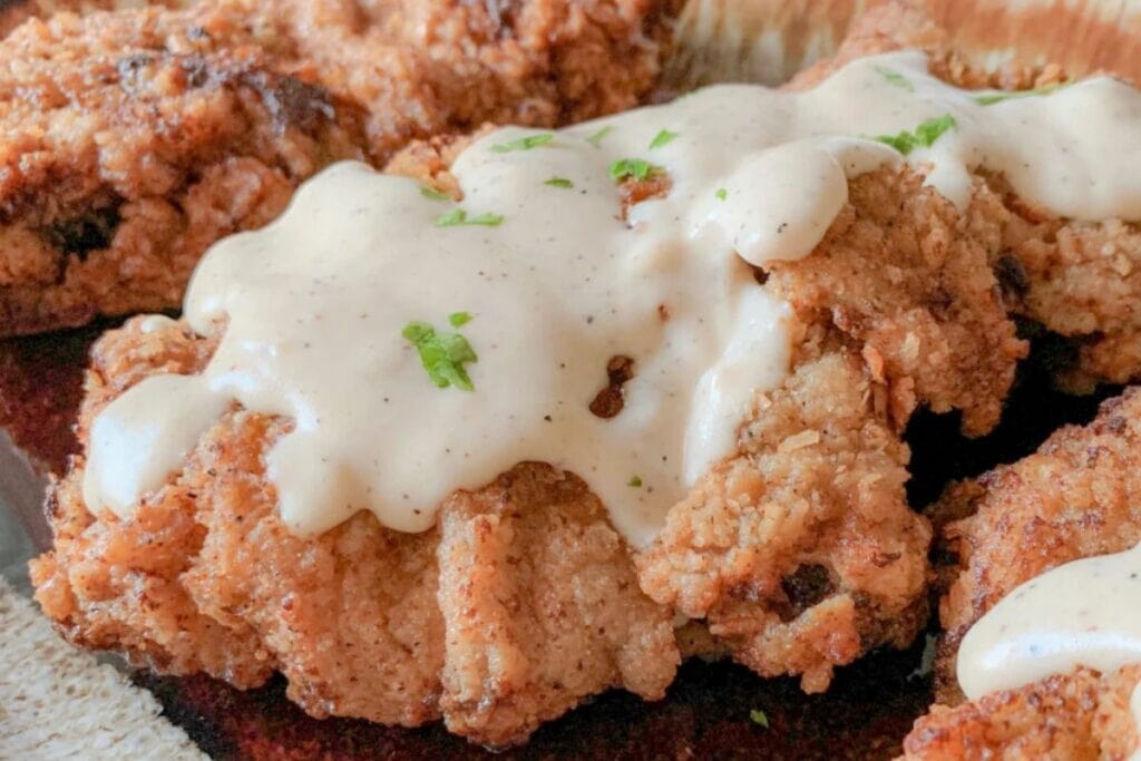 A close up shot of fried steak with sauce.