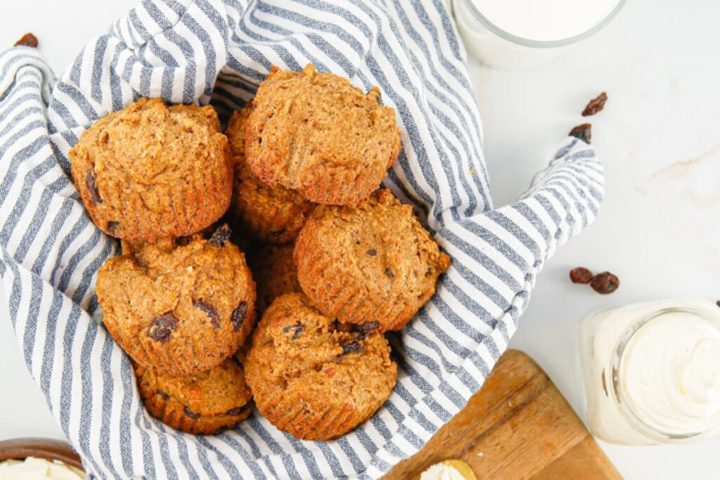 Bran muffins with raisins in a striped kitchen towel.