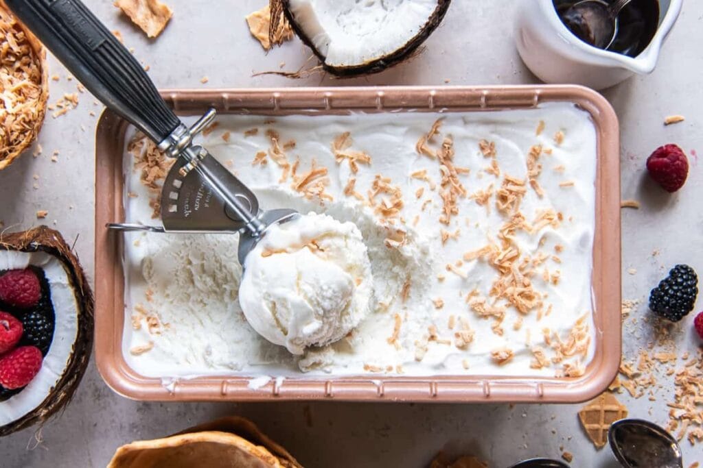 Coconut ice cream in a rectangular pan topped with toasted coconut flakes.