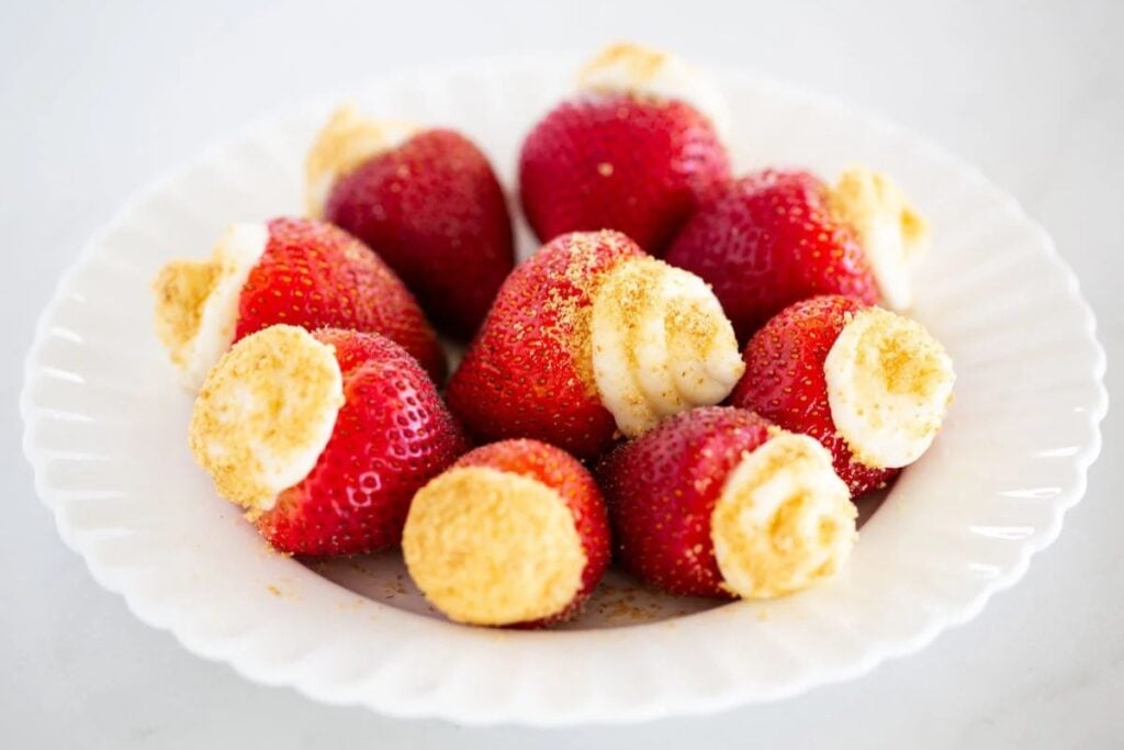 Cheesecake stuffed strawberries on a plate.