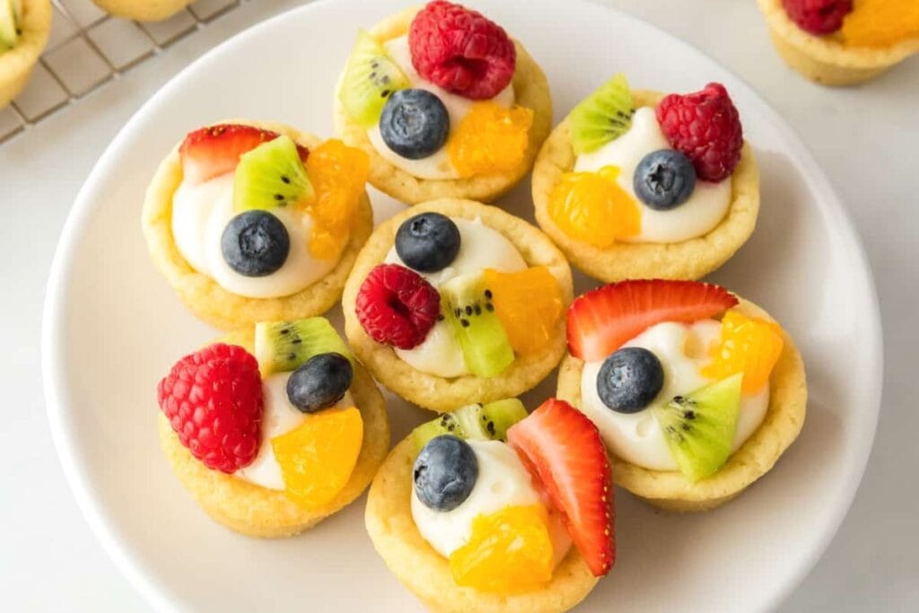 Mini cheesecake sugar cookie cups on white plate.