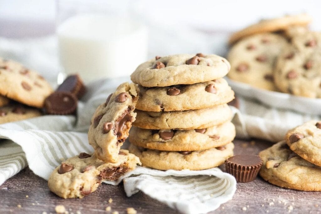 Stack of chocolate chip cookies stuffed with Reese&rsquo;s peanut butter cups on a table.